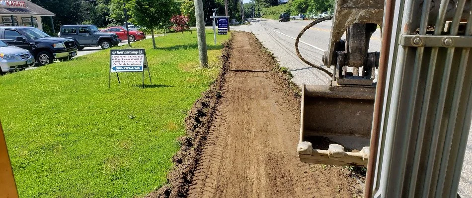 Excavator and a trench along a road in Groton, CT.