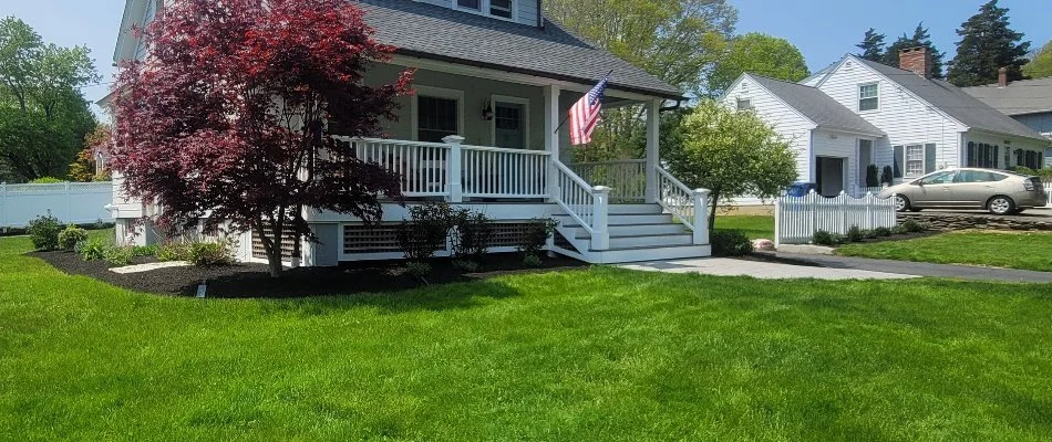 House in Stonington, CT, with lush lawn and a tree.