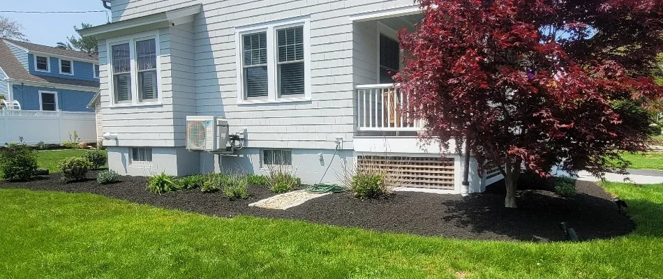 Neat landscape in Groton, CT, with mulch, tree, and small plants.