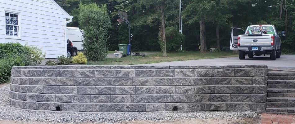 Retaining wall in Groton, CT, with a car and some plants.